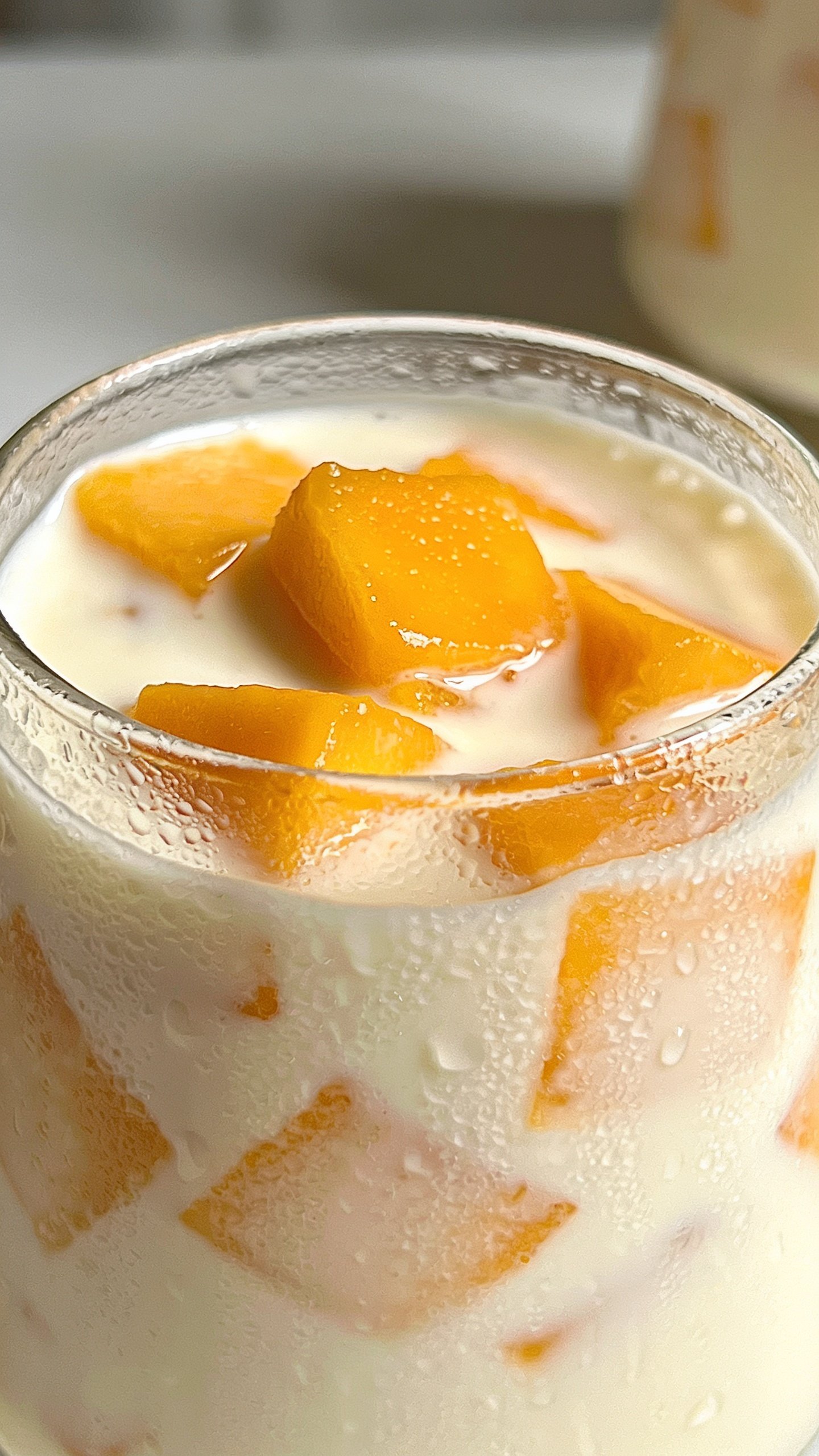 closeup of creamy mango yogurt smoothie in glass, condensation on cold glass