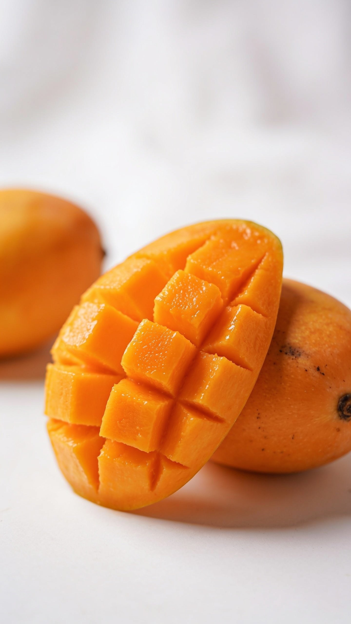 closeup of ripe mango half showing vibrant orange flesh against white background