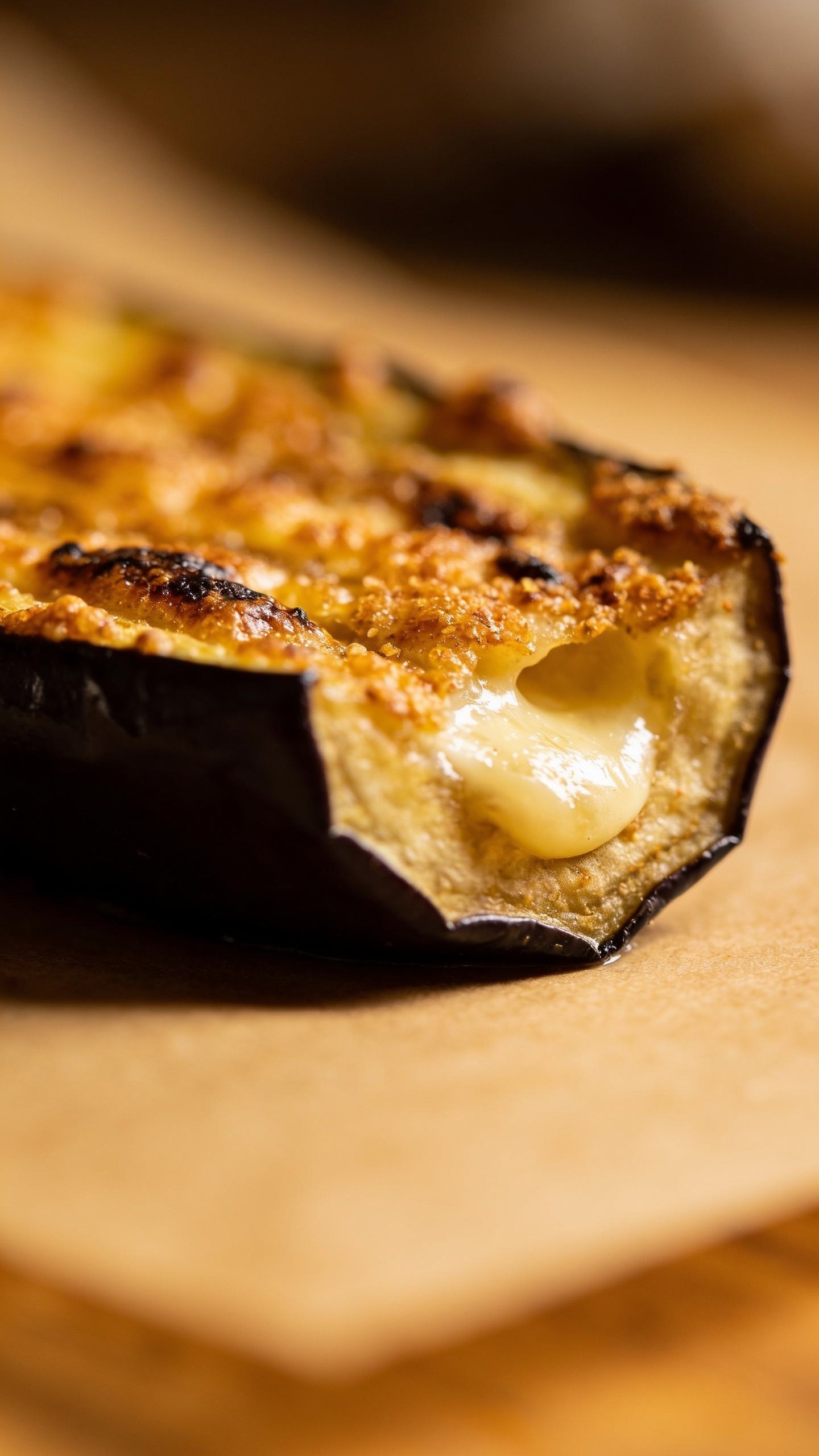 Closeup of a single roasted eggplant slice, crispy crust and melted interior