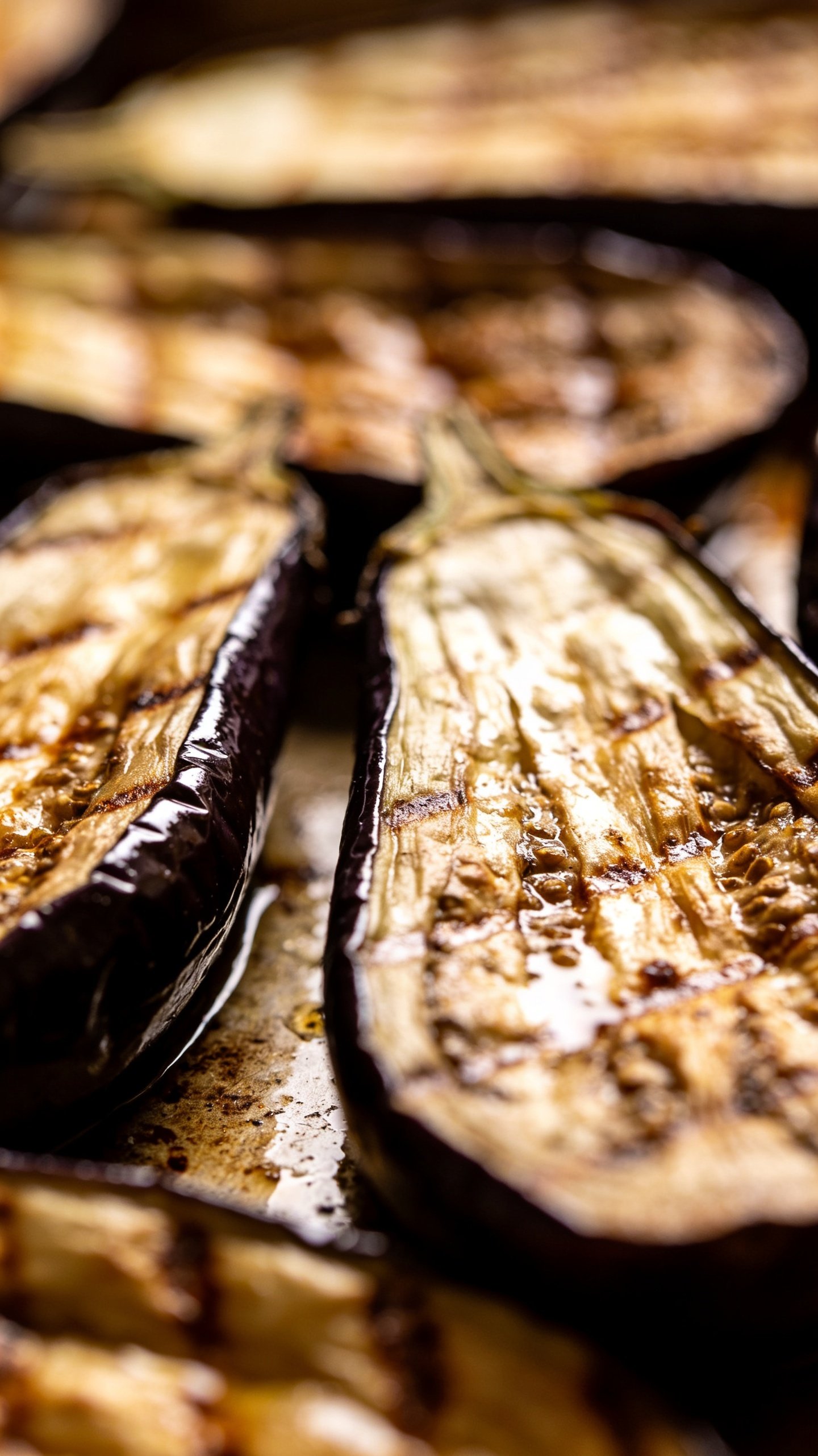 Closeup of roasted eggplant halves glossy skin, shallow depth of field