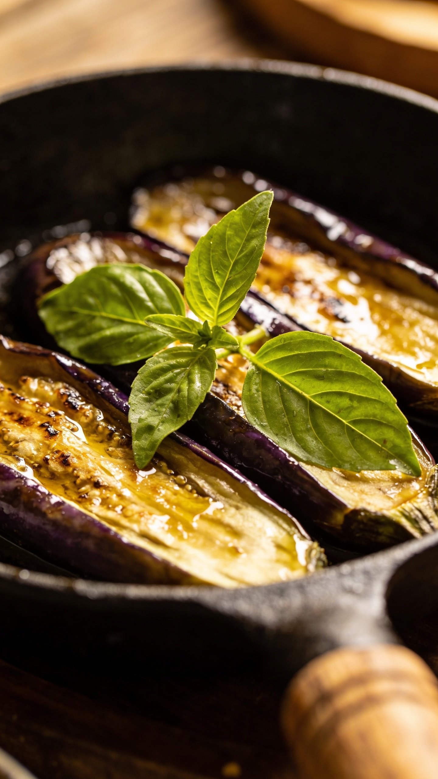 closeup of Thai basil leaves resting atop sizzling eggplant pan