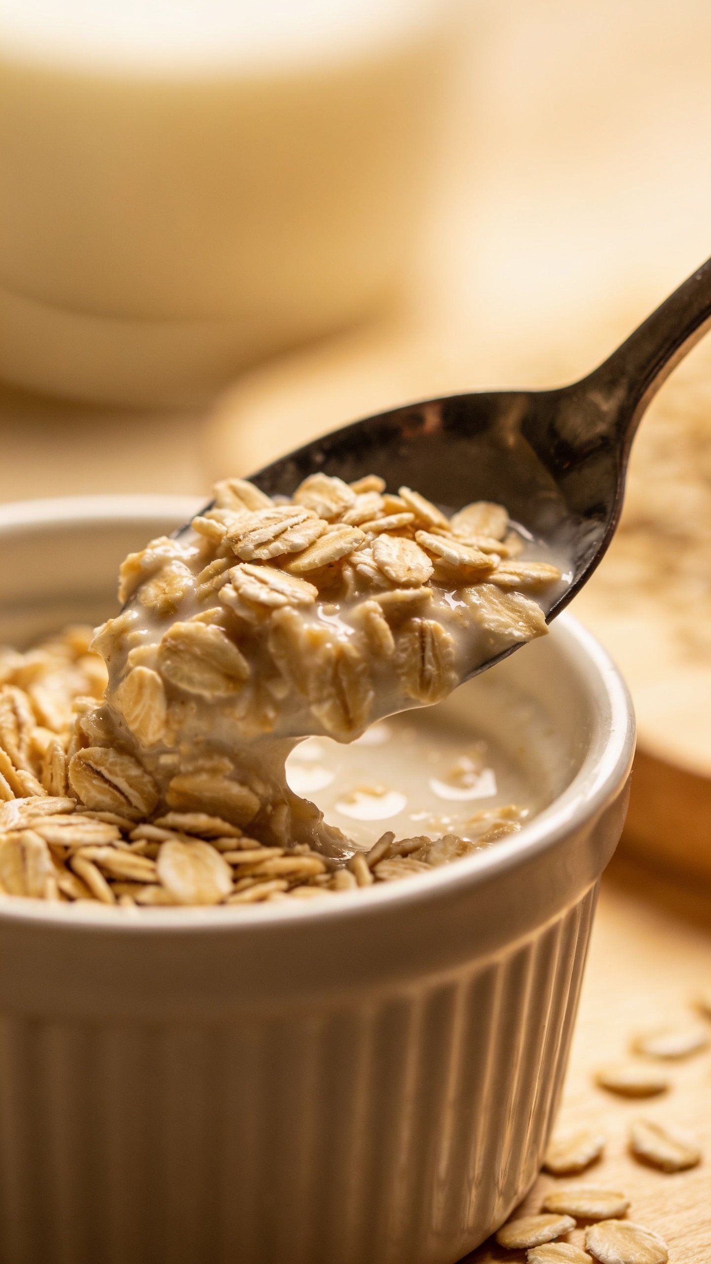 Side-profile closeup of spoon scooping oats from ramekin, creamy texture