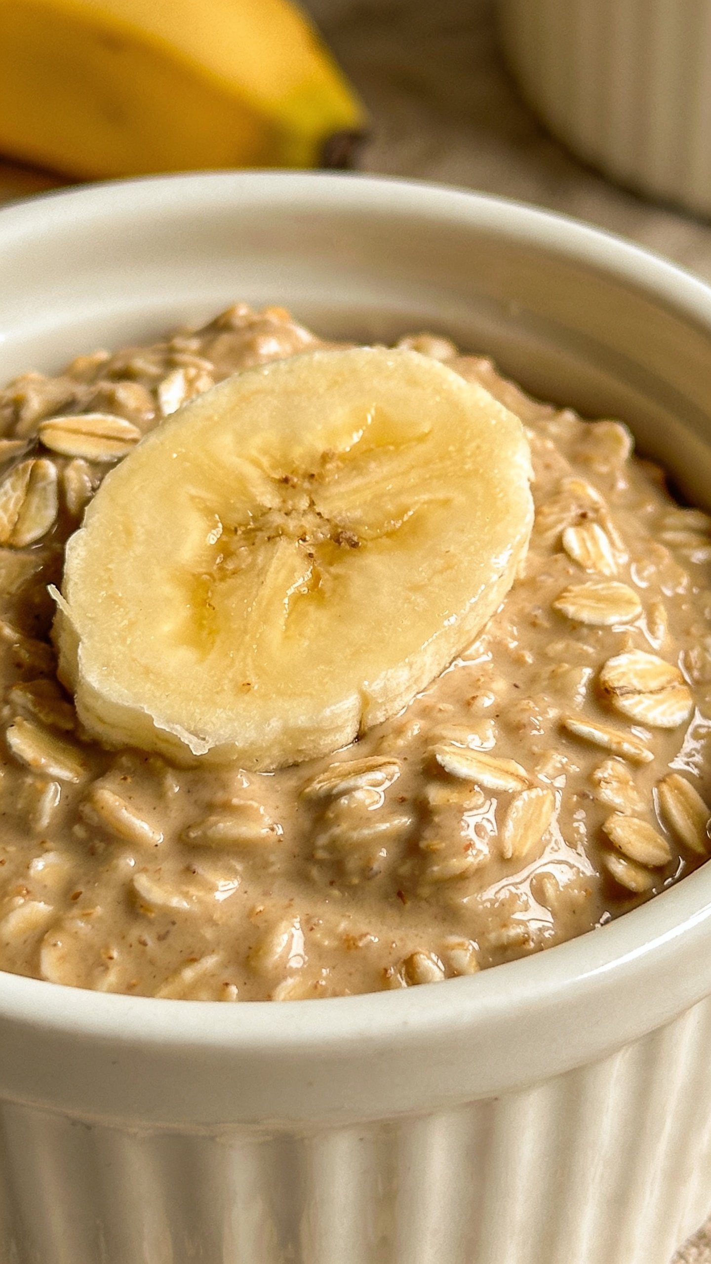 Closeup of oats batter in ramekin with ripe banana garnish, shallow depth of field