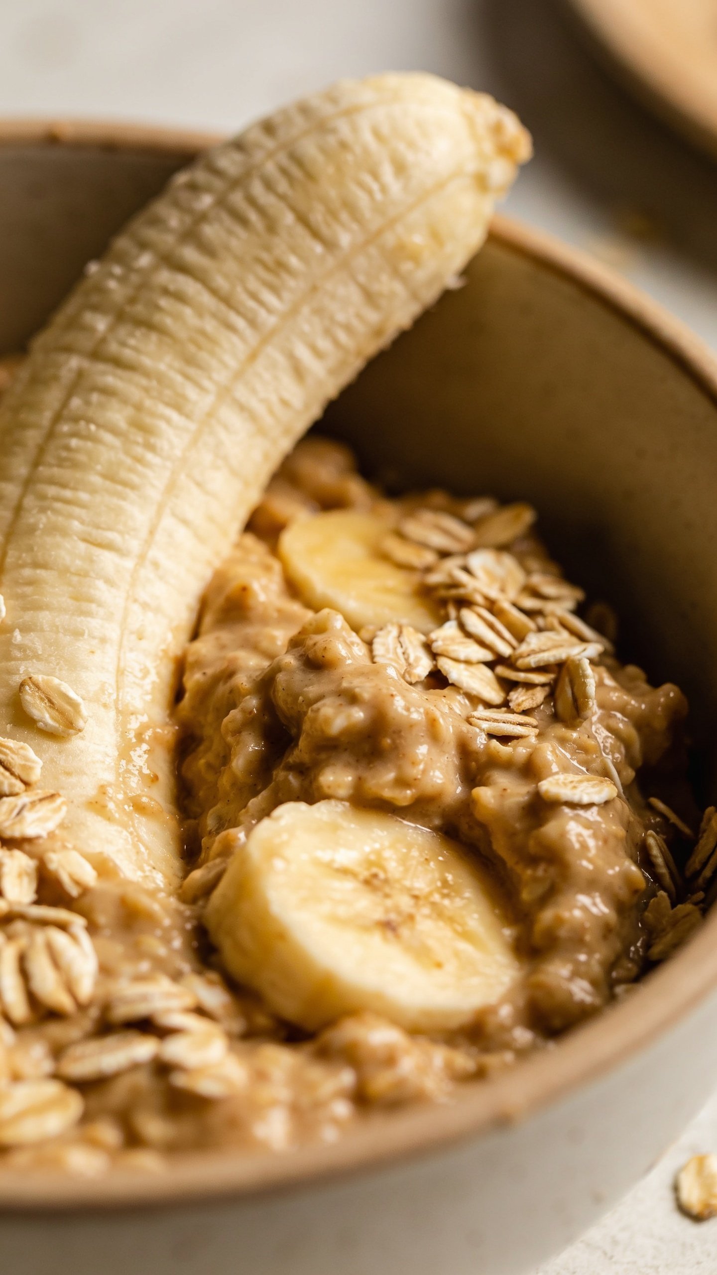 closeup of a single ripe banana mashed with oats batter in a bowl