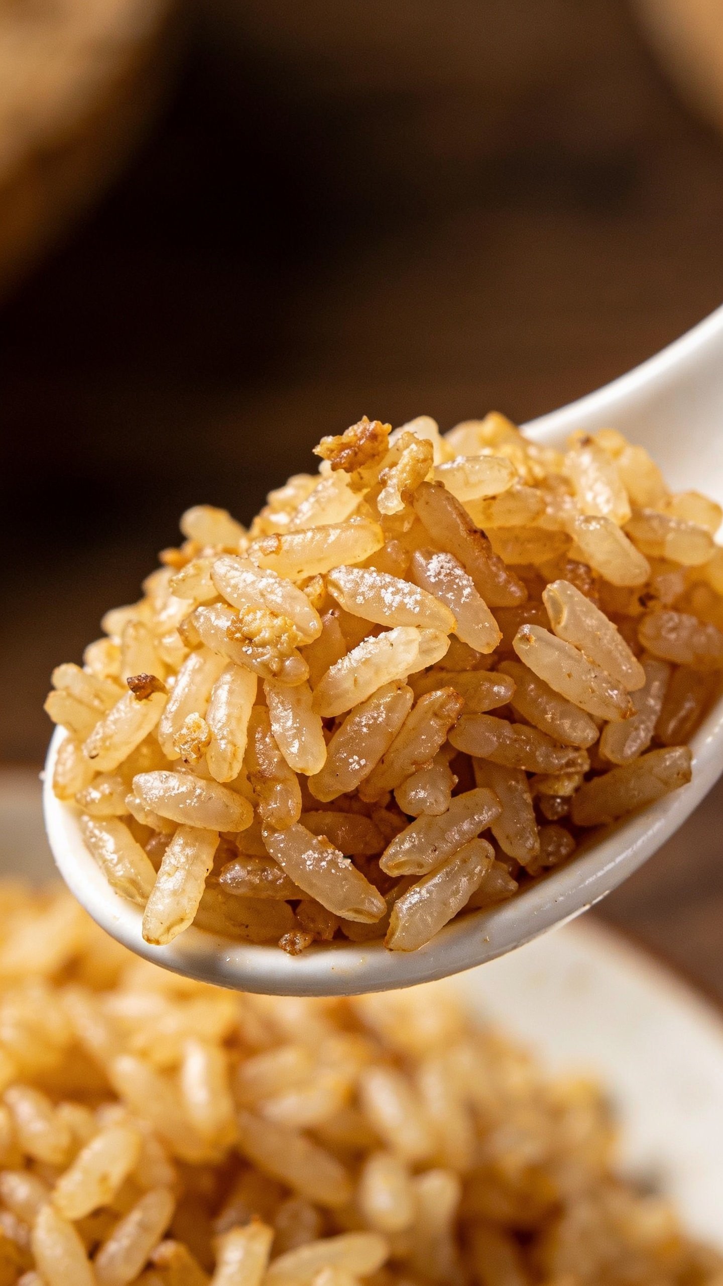 Closeup of day-old fried rice grains in a white spoon