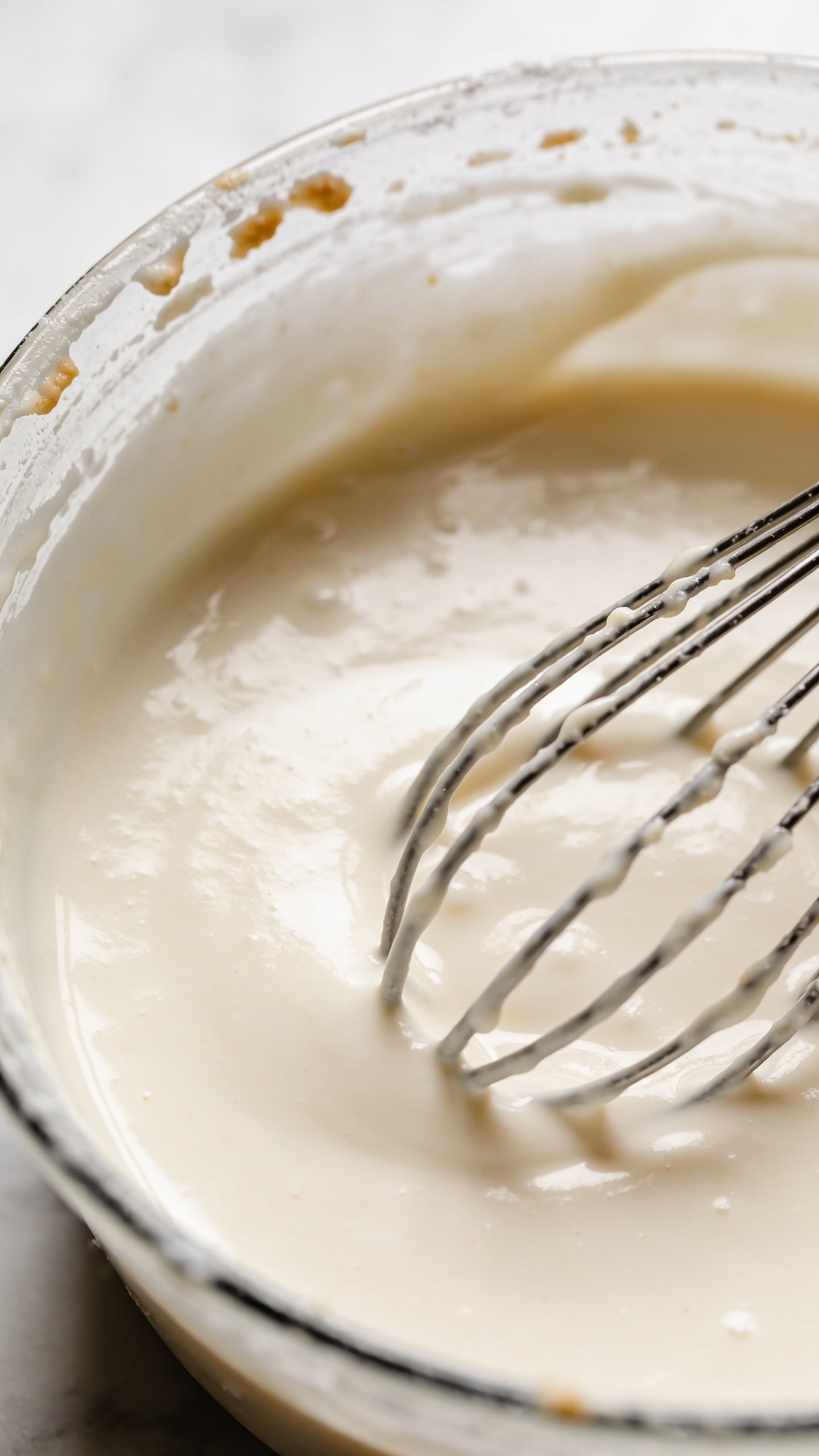 closeup of vanilla Greek yogurt container with whisk and batter residue