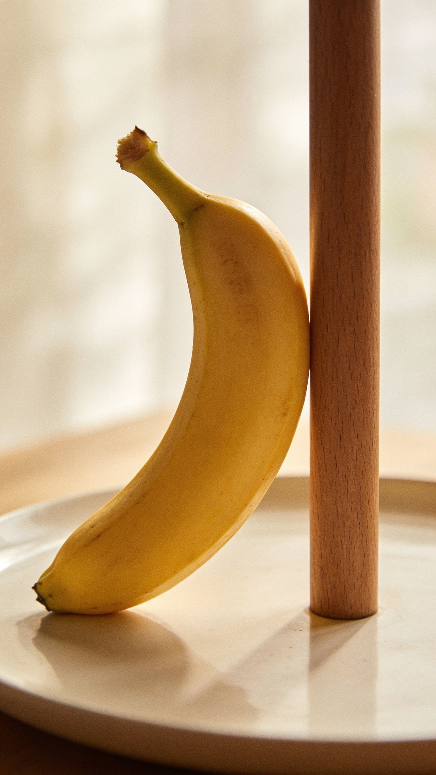 Single ripe banana beside bar, plain white plate, soft focus