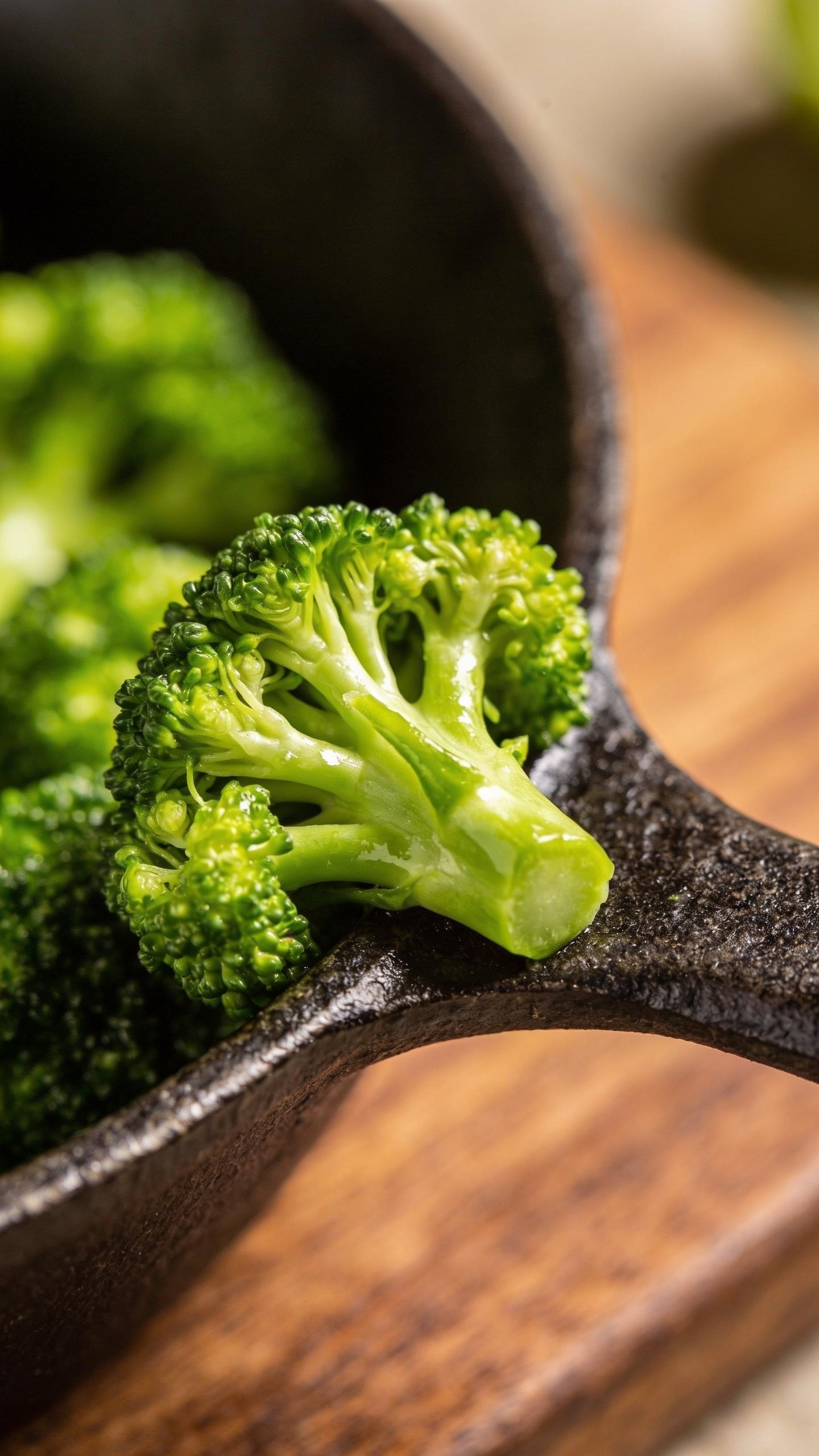 Closeup of vibrant broccoli florets on a textured skillet edge