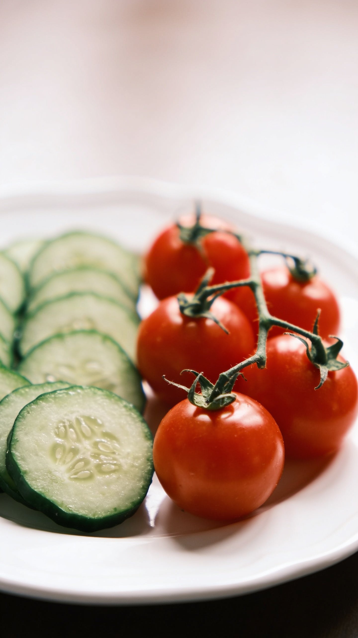 closeup of cucumber slices and cherry tomatoes on white plate